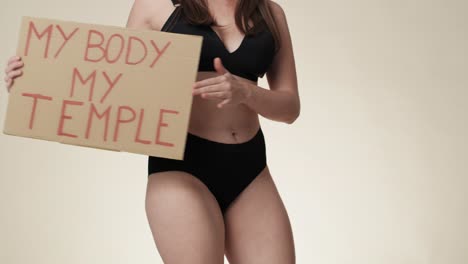 Unrecognizable-caucasian-woman-in-underwear-dancing-with-a-banner-in-the-studio.