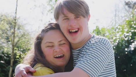 outdoor portrait of loving young downs syndrome couple in garden at home together