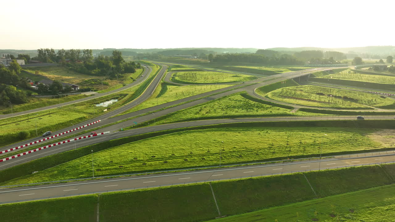 Sunset aerial of highway interchange with looping curves, fields, and countryside
