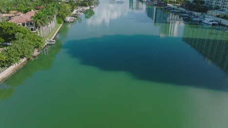 High-angle-view-of-turquoise-water-surface.-Tilt-up-reveal-view-of-buildings-in-urban-neighbourhood-in-tropical-city.-Miami,-USA