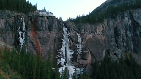 Bridal-Veil-Falls-Telluride-Colorado-Luftdrohne-Gefrorenes-Eis-Wasserfall-Herbstsonnenuntergang-Kühle-Schattige-Felsige-Berge-Silverton-Ouray-Millon-Dollar-Highway-Historische-Stadtlandschaft-Langsame-Abwärtsbewegung