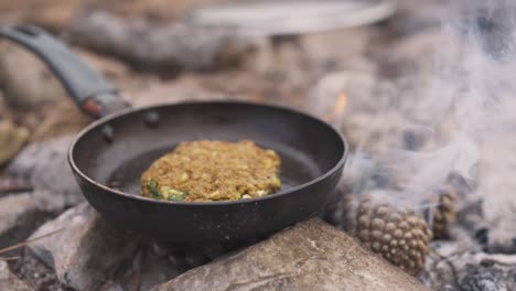 Hamburguesa-Vegana-De-Lentejas-En-Una-Sartén,-Cocinando-Comida-Usando-Una-Fogata,-Acampando-Al-Aire-Libre