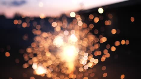 Slow-motion-shot-of-fireworks-going-off-on-the-ground,-as-the-flames-are-intentionally-out-of-focus-creating-beautiful-bokeh-bubbles-and-blurring