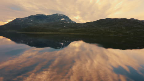 glorious sunset in vavatn lake in hemsedal with beautiful mountain reflection against cloudy sky - wide shot