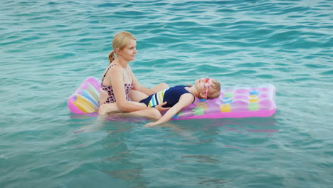 a young family is relaxing on the waves on an inflatable mattress