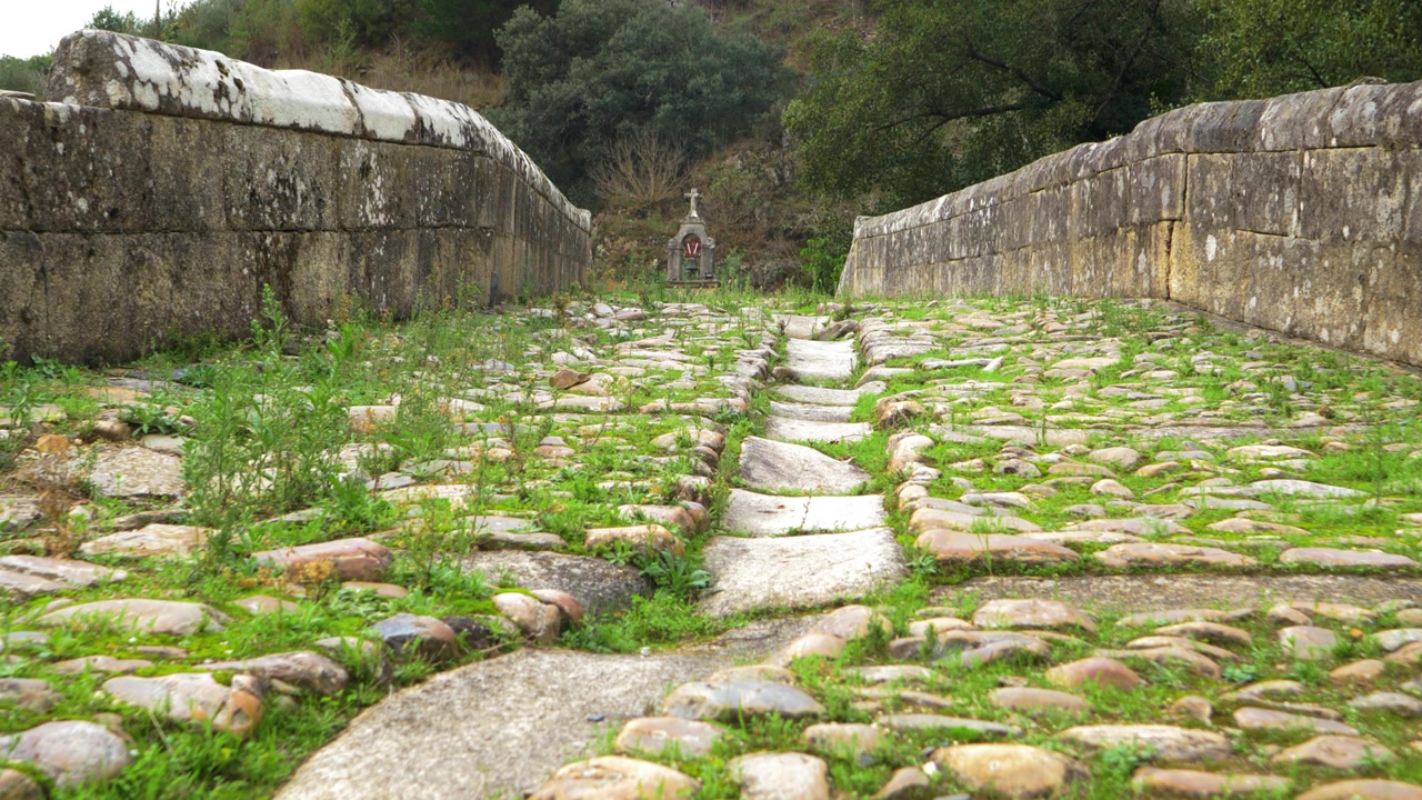 Old bridge cobblestones and stone parapets lead across Portomourisco in Petín, Galicia, Spain