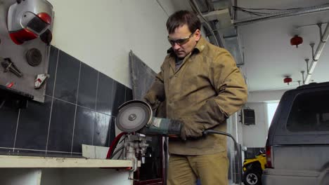 trabajador que utiliza un molinillo para cortar metal en un taller