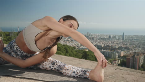 woman doing twisted head to knee pose outdoors. trainer exercising in city