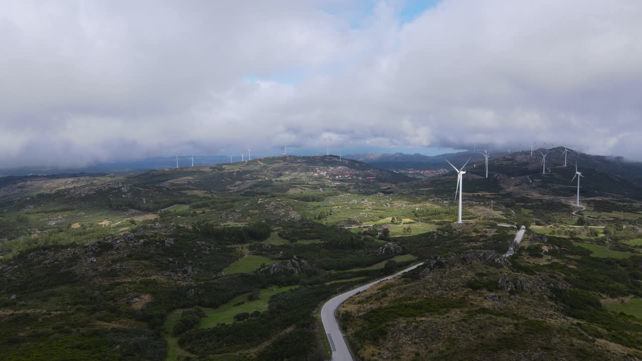 una persona en el mirador de caramulinho y aerogeneradores eólicos en segundo plano