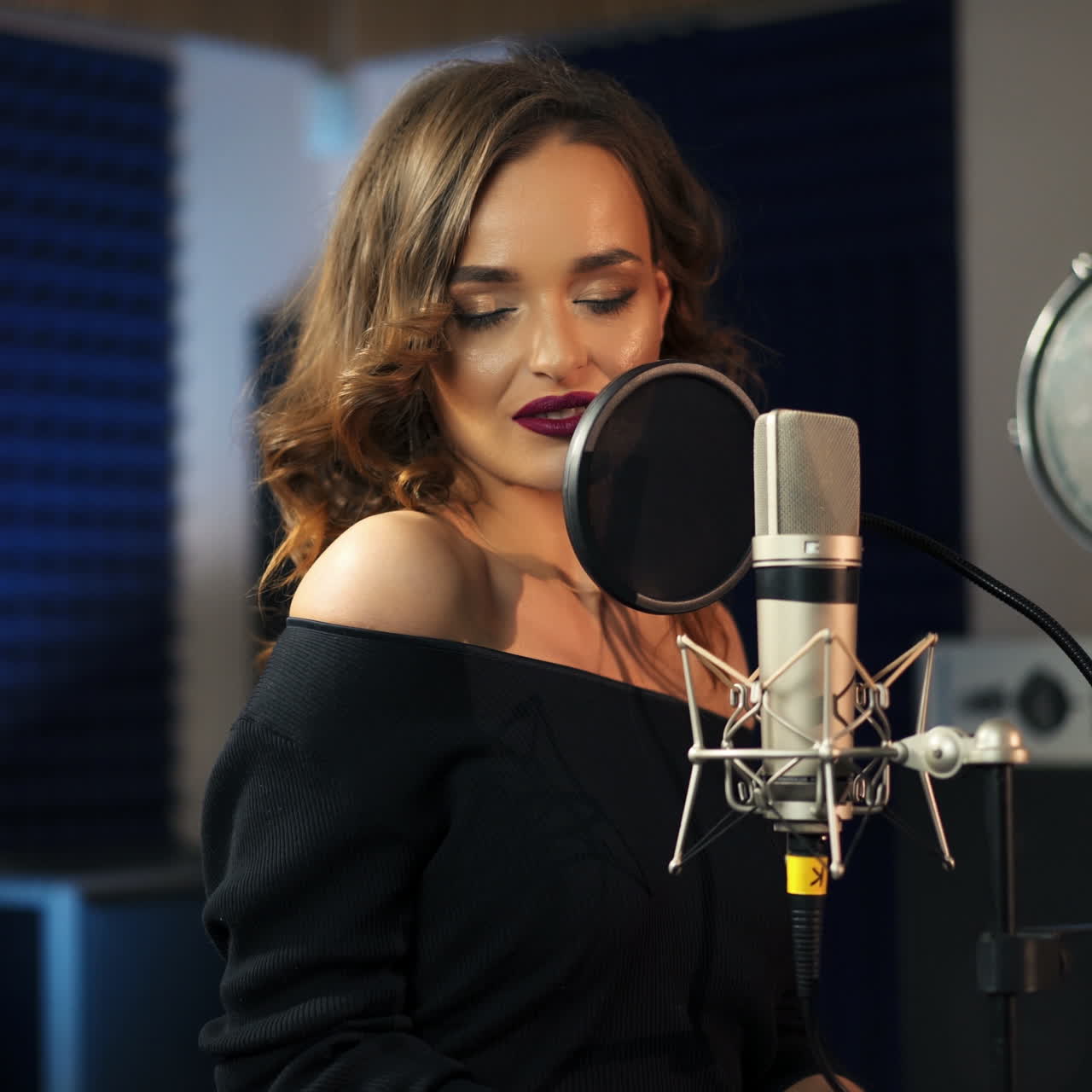 Bella donna che canta in un grande microfono. Studio di registrazione professionale. Video quadrato.