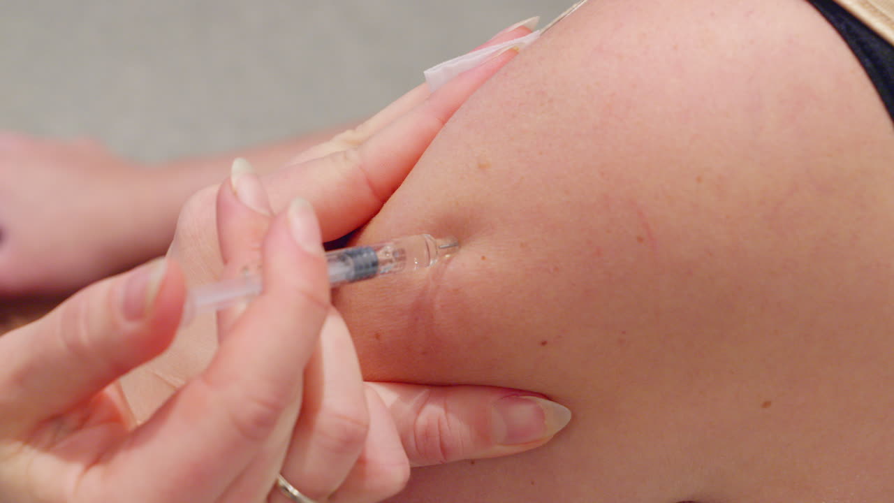 상부 팔에 들어가는 바늘의 근접 - 간호사가 주사한 백신