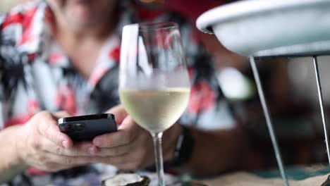 uso individual de teléfono inteligente junto a una copa de vino