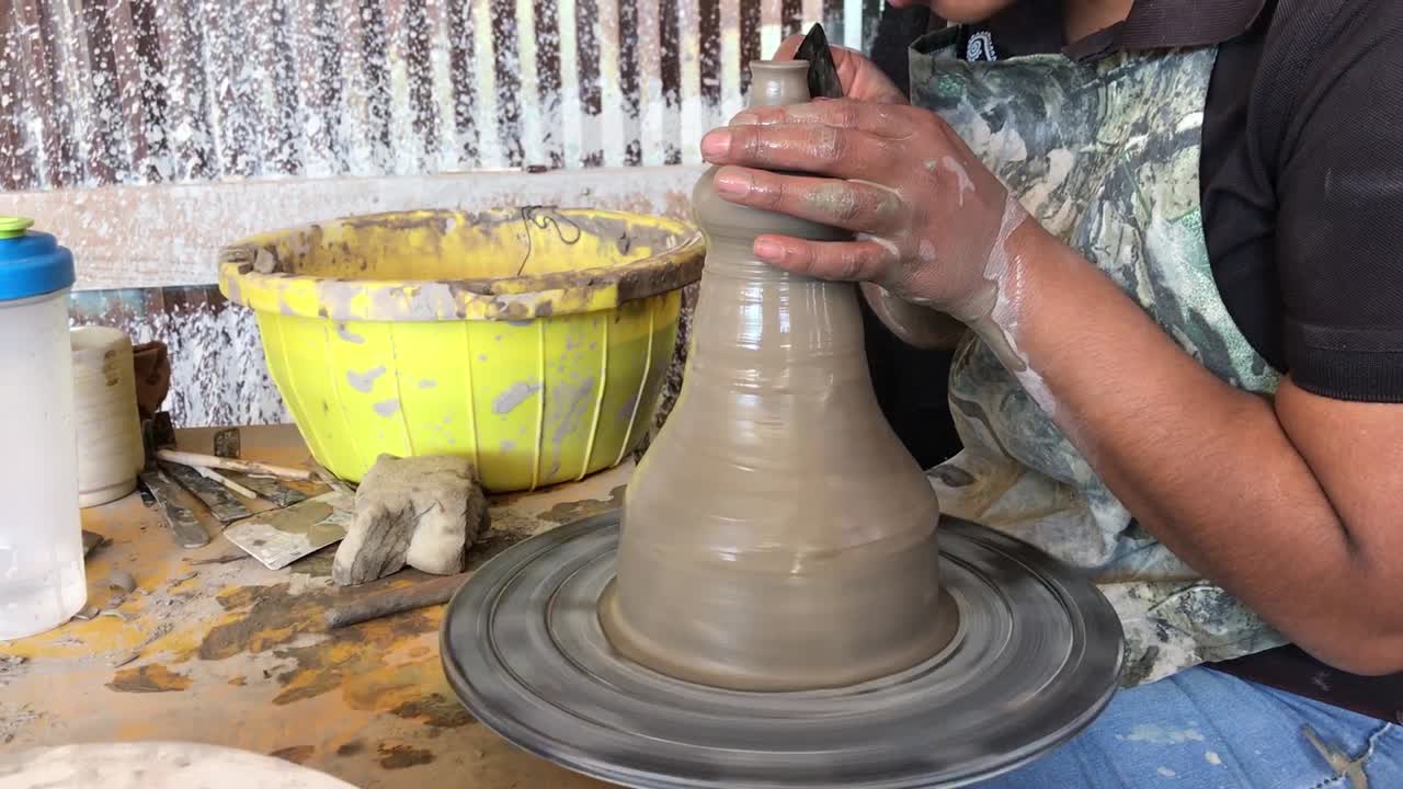 A woman creating a clay vase.