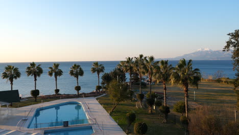 Resplandor-De-La-Puesta-De-Sol-Acercándose-A-La-Piscina-Del-Complejo-Con-Vistas-Al-Mar-Mediterráneo-En-Antalya,-Turquía