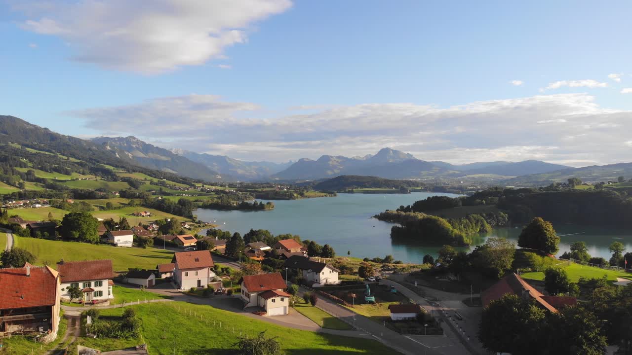 Veduta aerea con drone del paesaggio estivo svizzero, con il Lago di Gruyère e un villaggio.