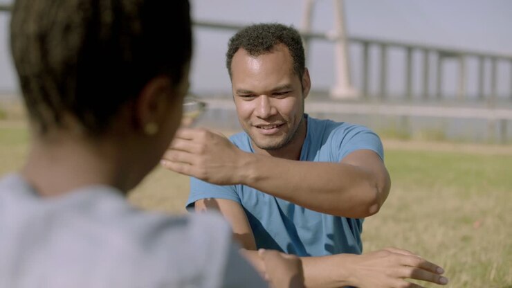 Smiling man playing with woman while sitting outdoor.