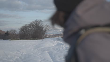 person in a jacket looks out at snowy landscape in hokkaido, japan near iwanai and niseko