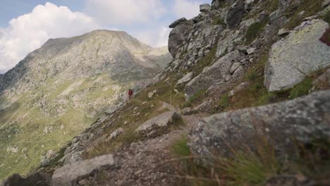 wide shot of hiker hiking along edge of steep cliff scarp during sunny and cloudy day in italy