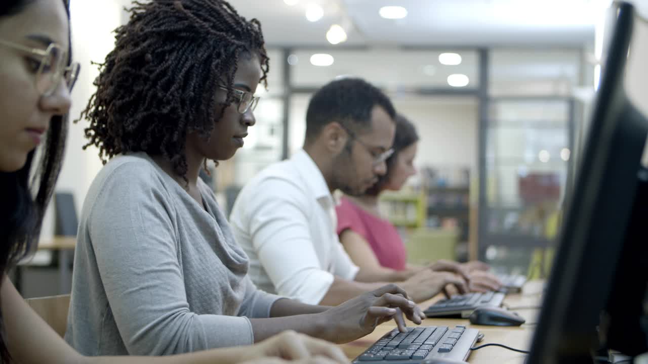 Side view of people sitting at tables and working with computers