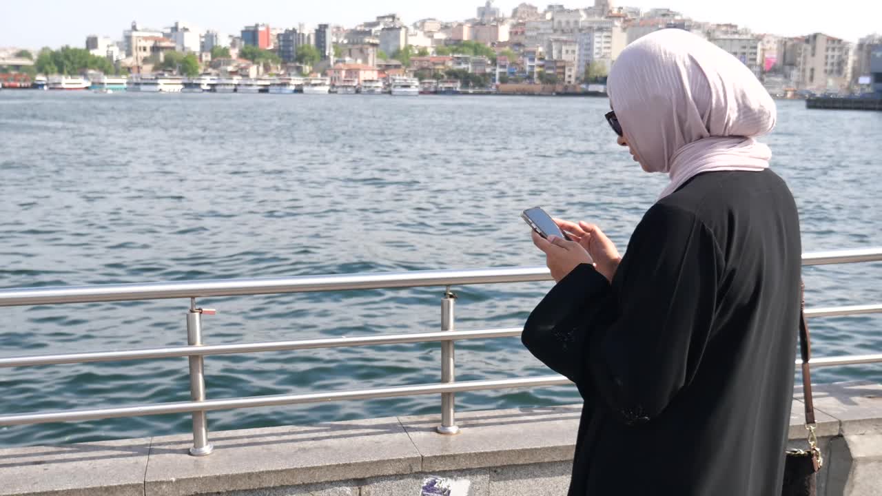 Woman using phone by the waterfront in a city