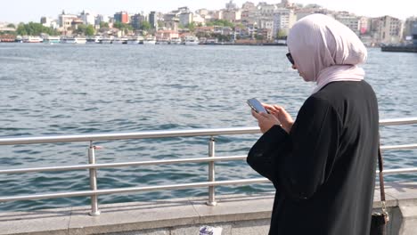 woman using phone by the waterfront in a city