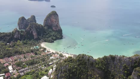 aerial flying over forested cliff to reveal idyllic beach in railay with ocean sea view