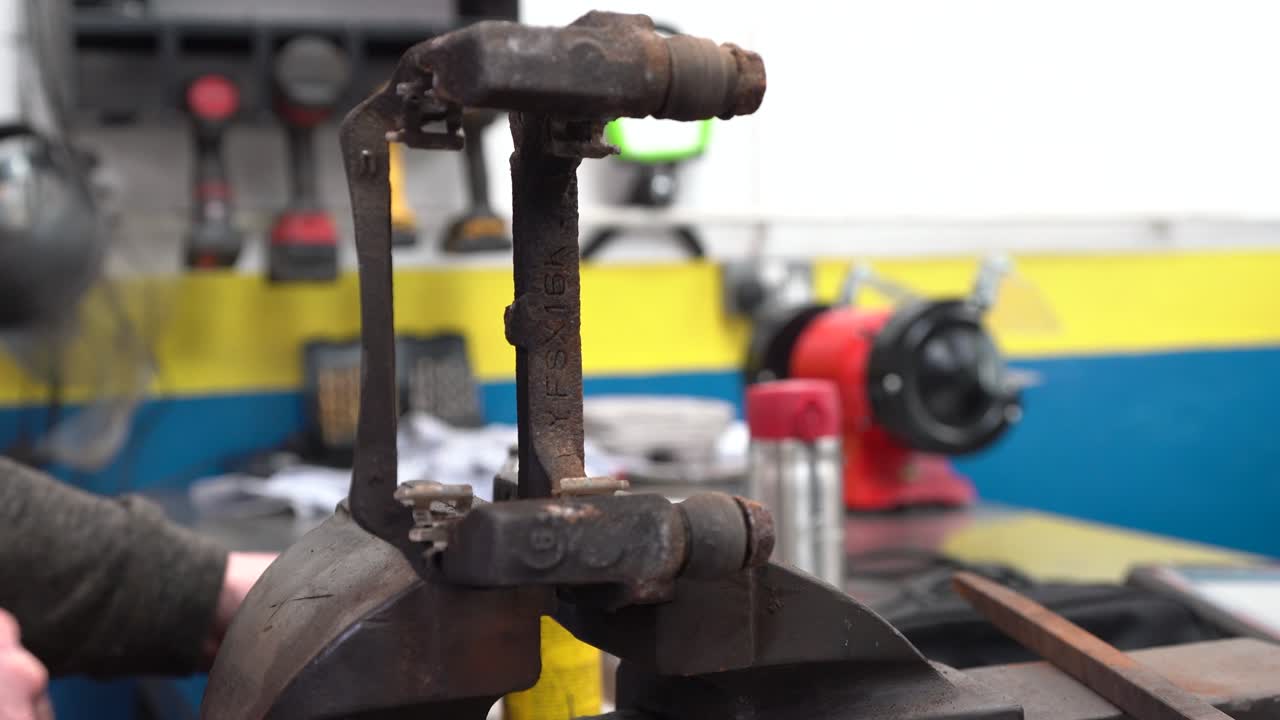 Mechanic Cleaning Rusty Brake Caliper in Auto Repair Shop