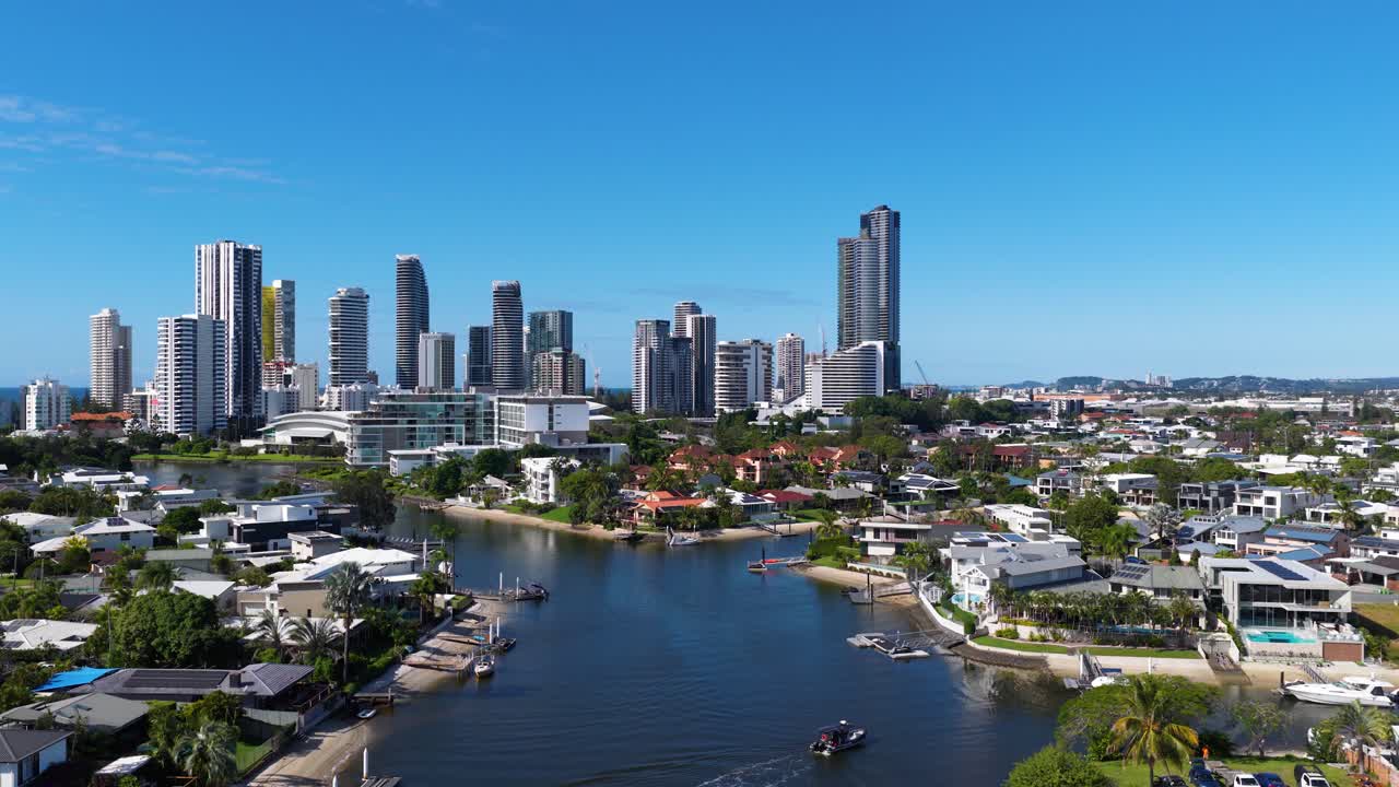 Aerial footage captures the Gold Coast skyline with high-rise buildings and serene waterways under clear blue skies