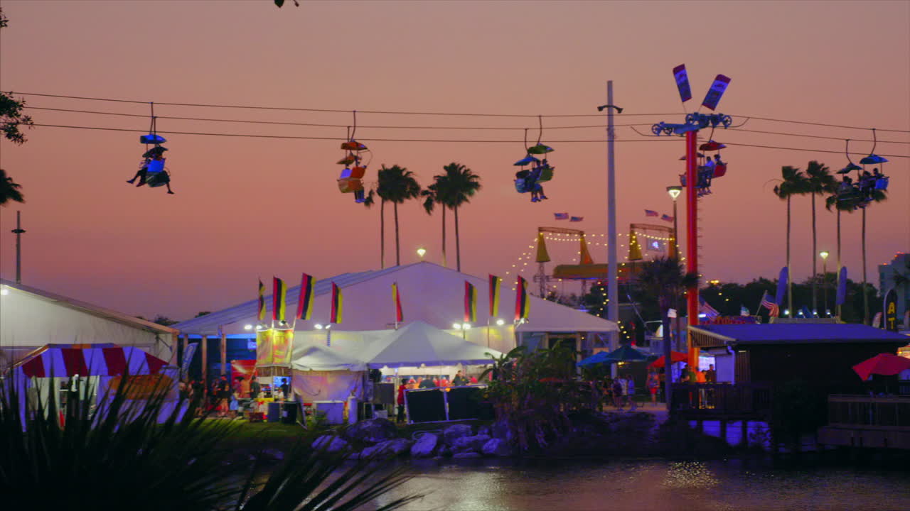 Panning across a colorful fair sky ride vista at dusk