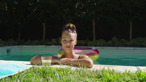woman relaxing by pool with drink, enjoying sunny day outdoors, copy space