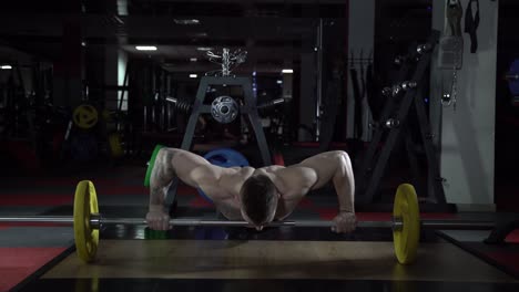 man doing weighted push-ups in gym