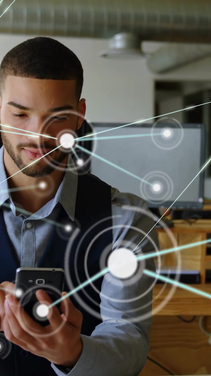 Man at desk holding smartphone, tapping screen and growing tech HUD with nodes visualizing network