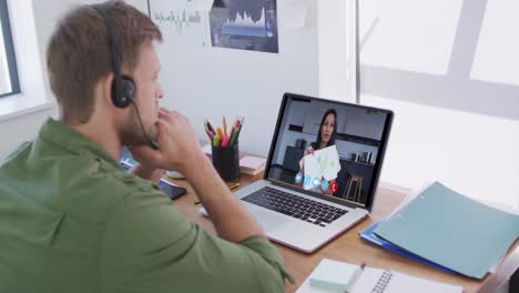 Caucasian-man-using-laptop-and-phone-headset-on-video-call-with-female-colleague