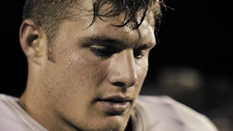 intense football player closeup revealing raw determination, glistening with sweat under stadium lights during high stakes night game, embodying unwavering competitive spirit