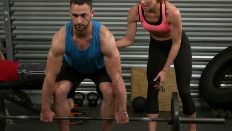 hombre en forma levantando pesas con entrenador