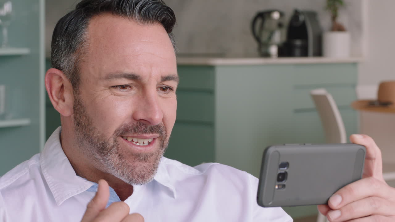 joven atractivo teniendo video chat usando smartphone disfrutando de charlar con un amigo en línea compartiendo estilo de vida relajándose en casa