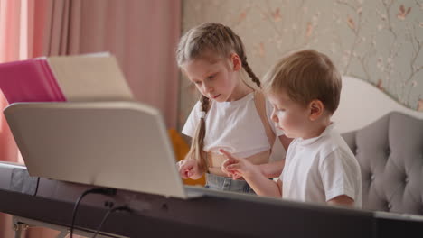 Little-girl-takes-brother-hand-and-presses-piano-keys