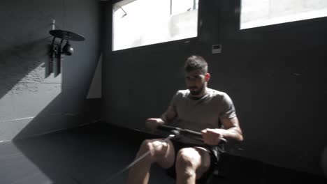 young athletic man doing exercise in the gym at the rowing machine