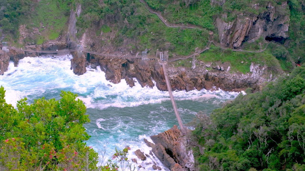 Top angle view of frothy seawater under Storms River mouth suspension bridge