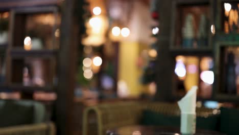una escena de restaurante suavemente iluminada con figuras borrosas y iluminación ambiental, creando una atmósfera cálida e íntima