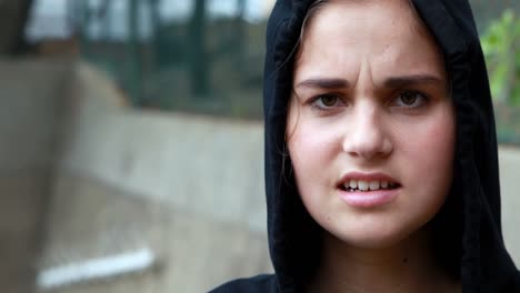 anxious teenage girl standing in black hooded jacket