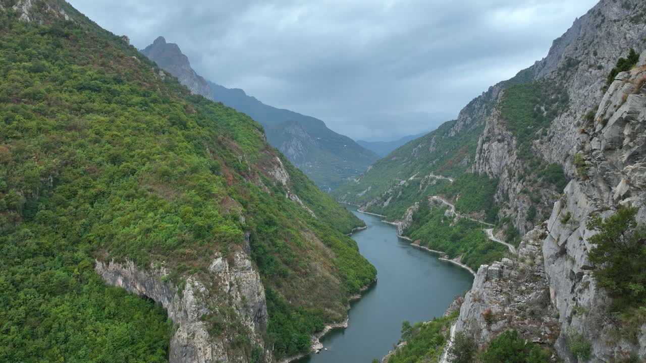 Wide rising aerial of Shala River between mountains in cloudy Albania