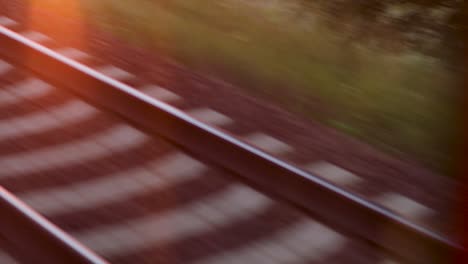 mirar por la ventana de un tren rodante, vías ferroviarias en movimiento rápido en el atardecer