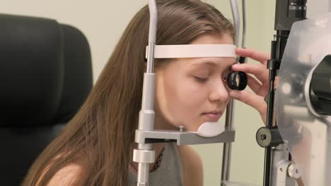 oftalmólogo chequea la vista de un adolescente con equipos modernos. médico chequeando los ojos con un dispositivo de biomicroscopio. toma de dolly de una doctora examinando la estructura del ojo con la ayuda de equipos médicos