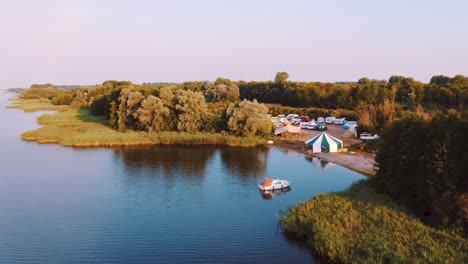 aerial drone reveal wildeburg festival camp site next to lake, early morning