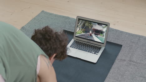 woman practicing yoga at home via online video tutorial