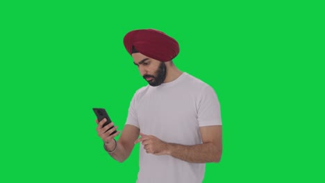 Sikh-Indian-man-scrolling-phone-Green-screen