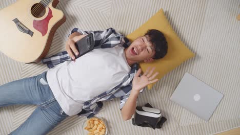 teenager relaxing at home with phone, vr headset, and guitar