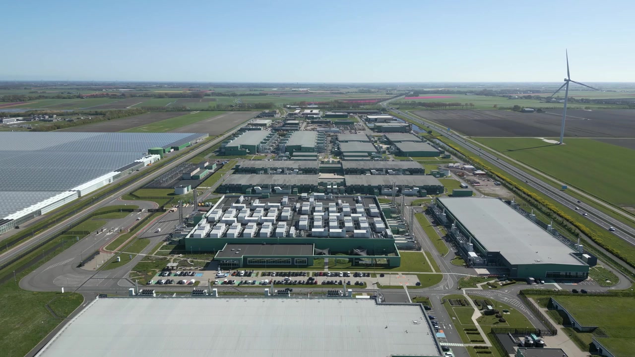 Droneoptagelser viser et massivt hyperscale datacenterkompleks omgivet af landbrugsjord og motorveje i Holland.