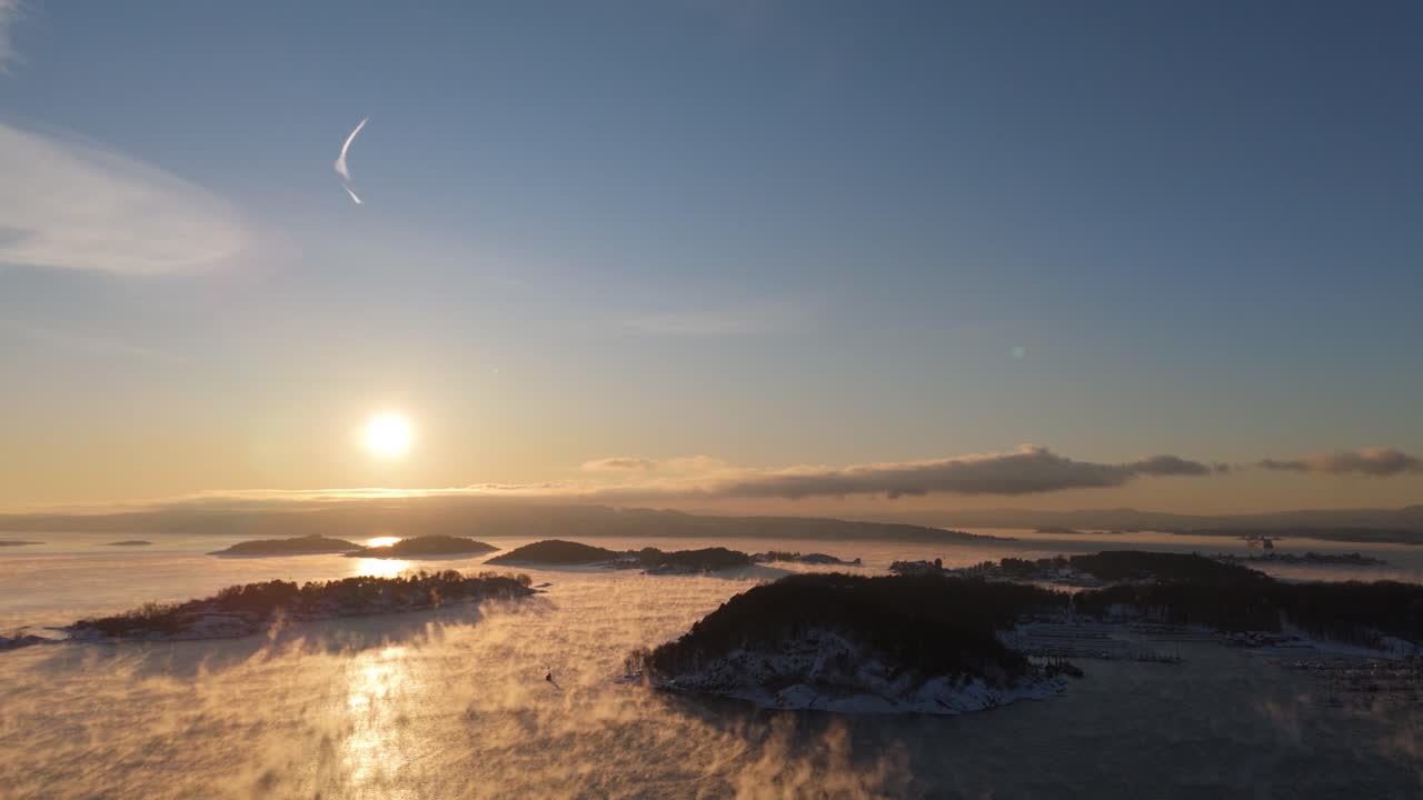 오슬로의 bjorvika 근처의 섬의 실루이트와 함께 지평선에서 황금 시간 해가 지는